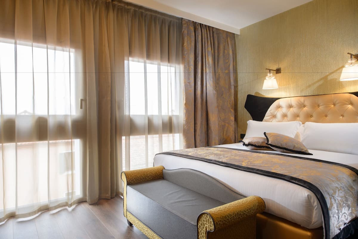 Ein Hotelzimmer mit einem großen Bett, einer Sitzecke und einem Fenster mit Vorhängen.