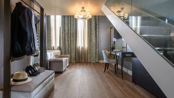 Un corridoio moderno di un hotel con una scala, un'area salotto con una panca e un piccolo tavolo con sedie.