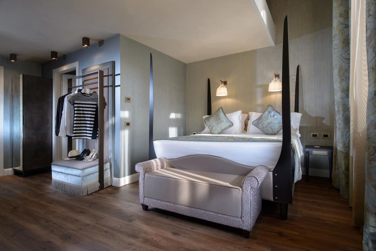 Ein modernes Hotelzimmer mit einem großen Bett, einer Sitzecke, einem Schminktisch und einem Kleiderständer.