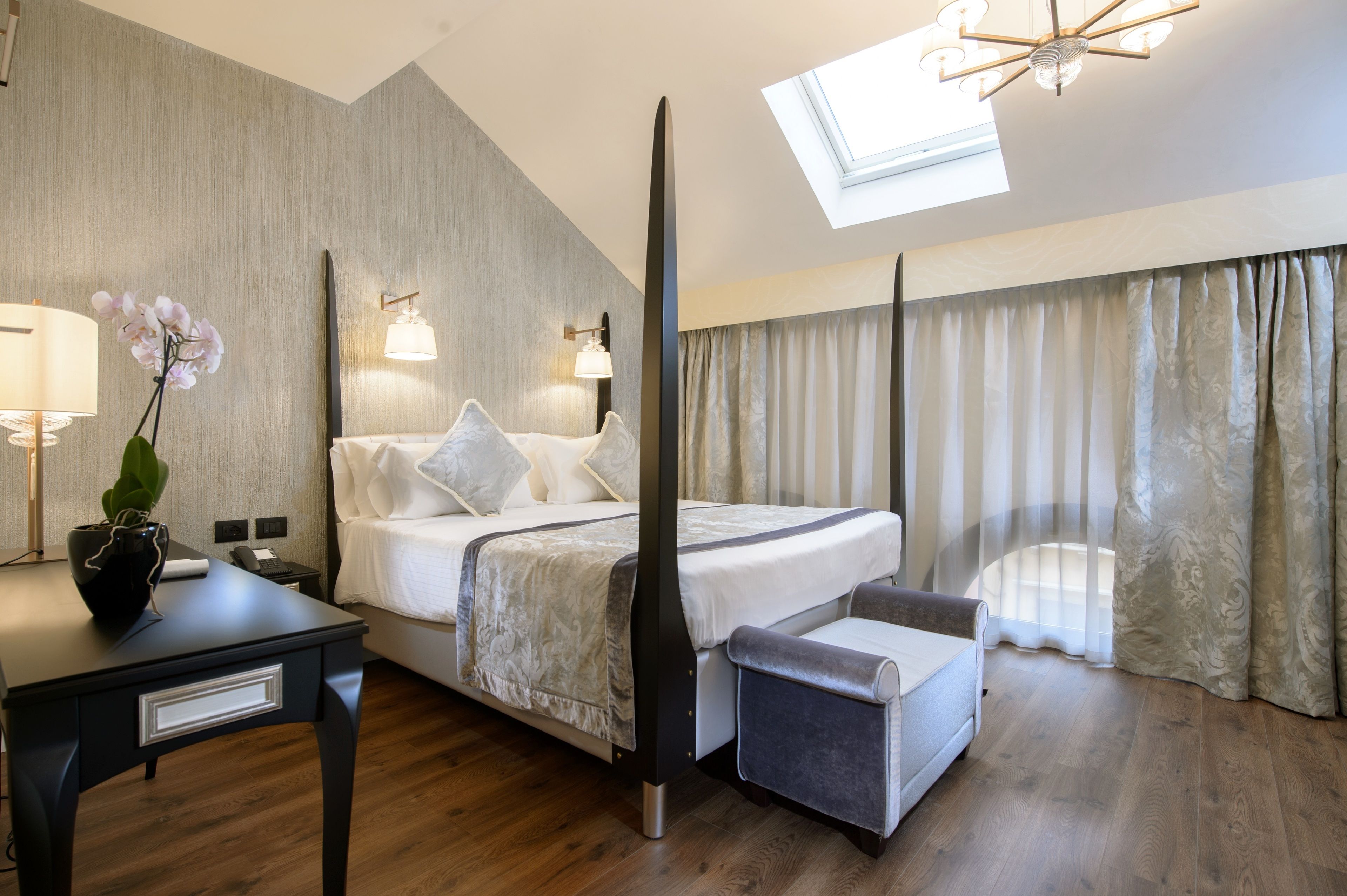 Una habitación de hotel moderna con cama, mesita de noche, lámpara y una planta en maceta.