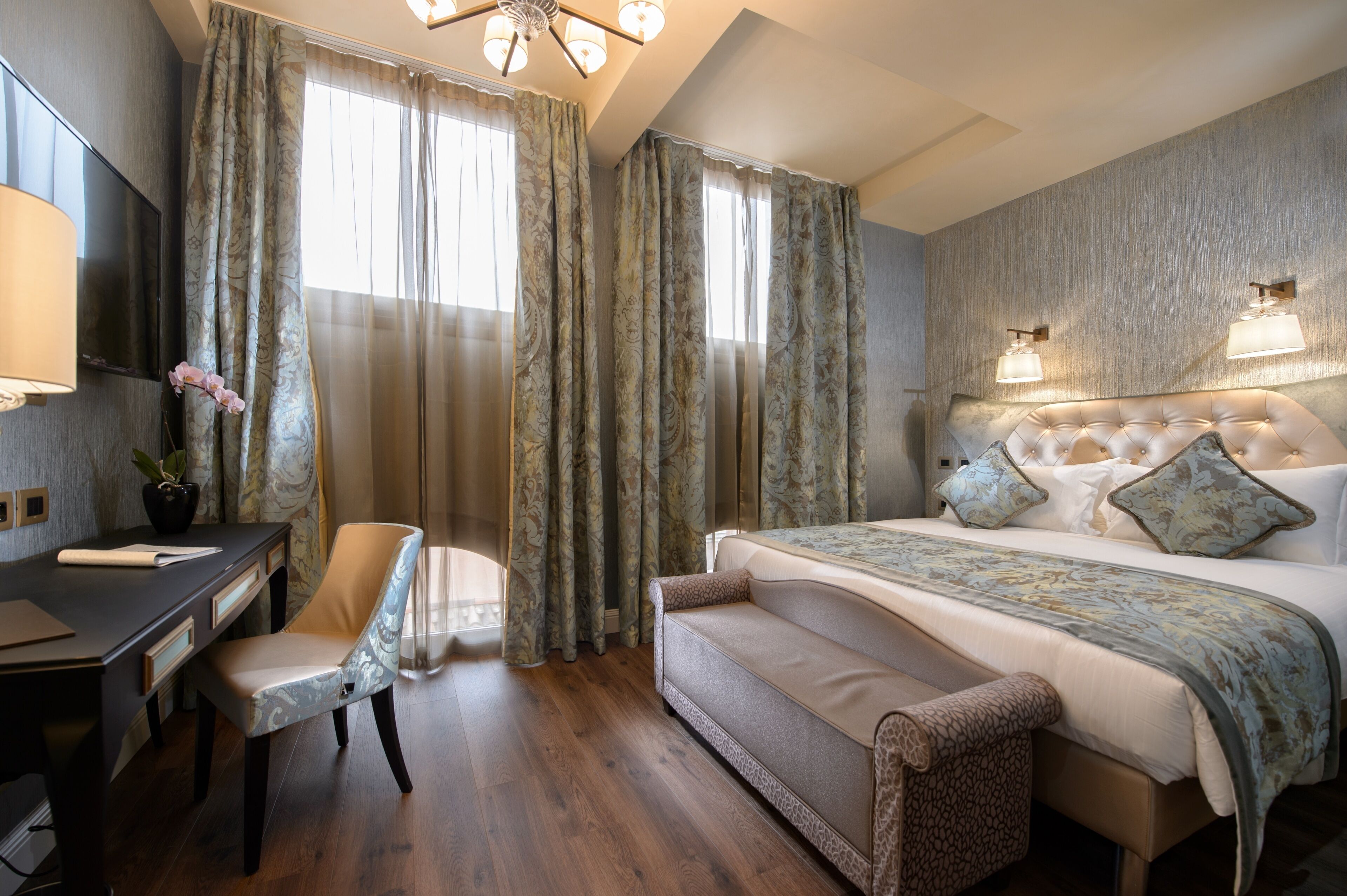 A hotel room with a bed, a desk, a chair, and a TV.