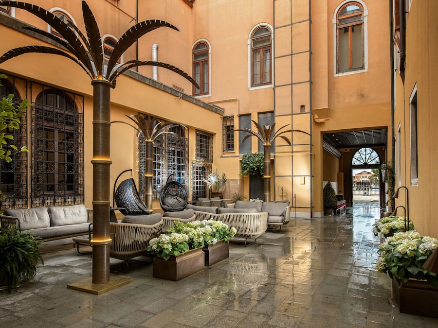 A spacious courtyard with a seating area, palm trees, and potted plants.