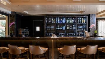 A bar area with a marble countertop, multiple liquor bottles, and bar stools.