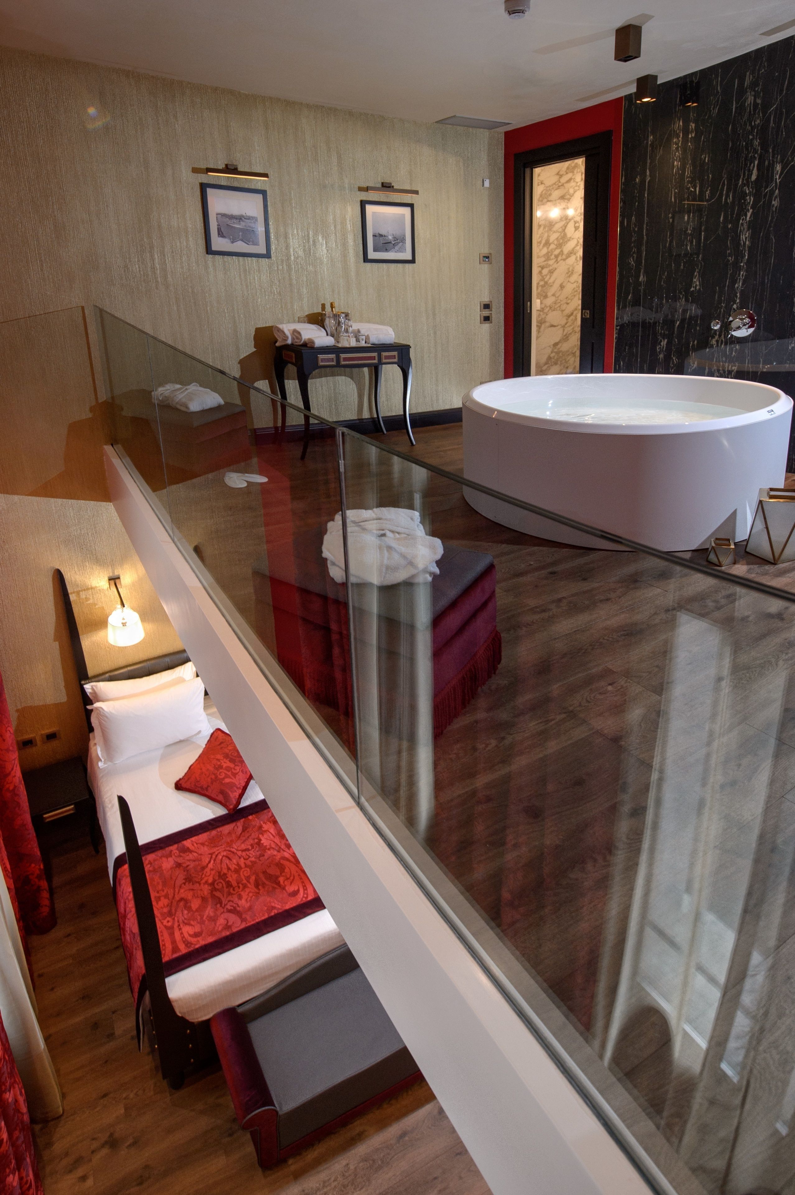 Quarto de hotel moderno com varanda envidraçada, uma banheira grande e área de estar com mesa e cadeiras.