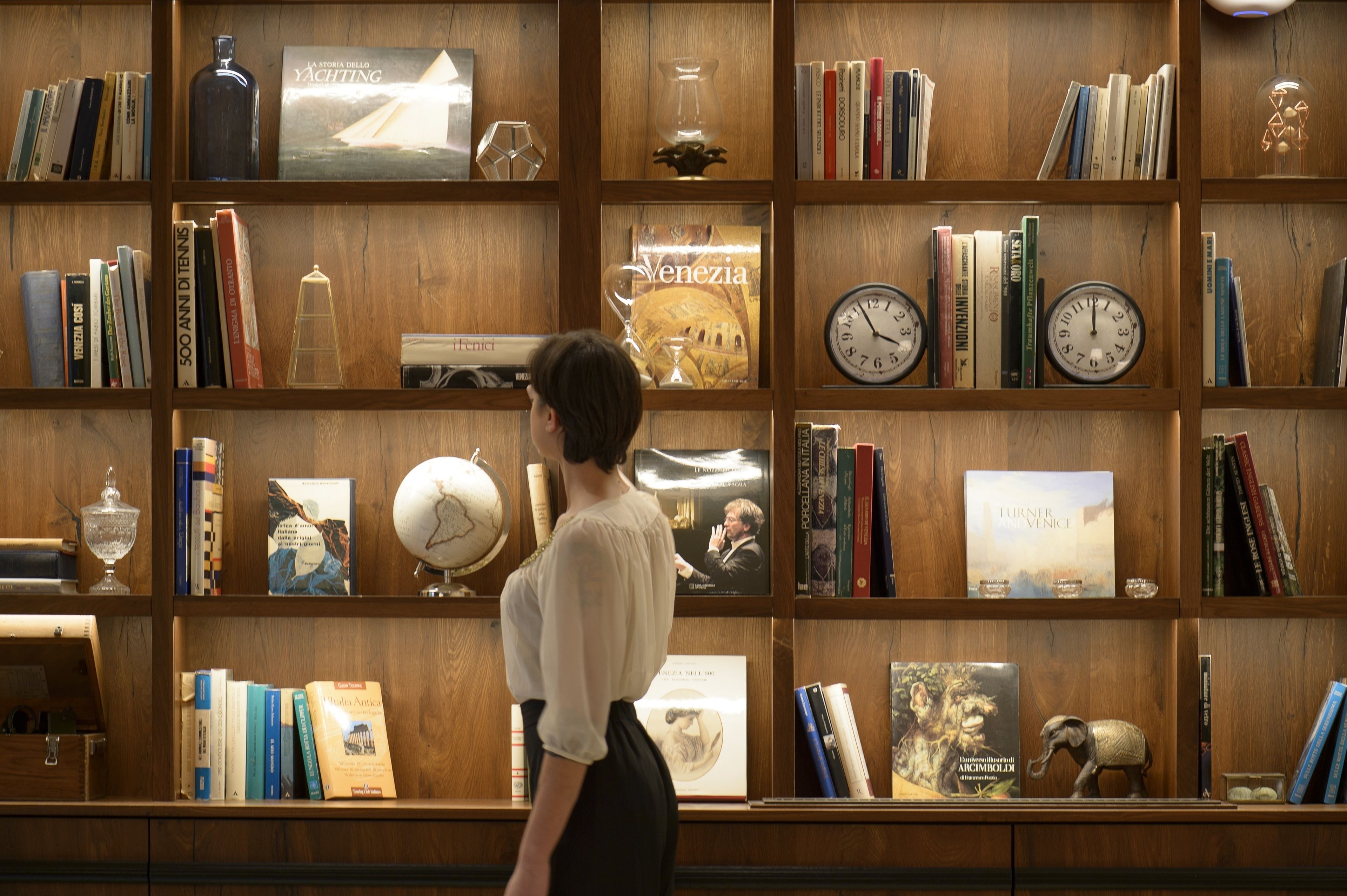 Una estantería de madera llena de libros, globos terráqueos y objetos decorativos.
