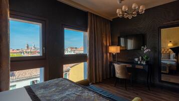 Habitación de hotel con una cama grande, un escritorio, una silla, un televisor y vistas a la ciudad.
