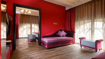 Una sala de estar moderna con una pared roja, piso de madera, un sofá morado y una mesita auxiliar pequeña.