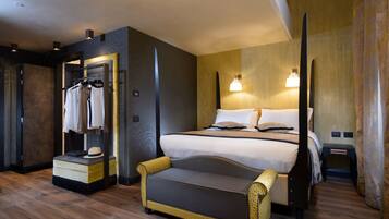 A modern hotel room with a large bed, a sofa, a wardrobe, and a nightstand.