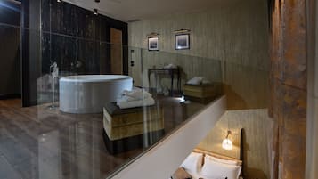 Un baño moderno con una bañera grande, un tocador con mampara de vidrio y un banco de madera.