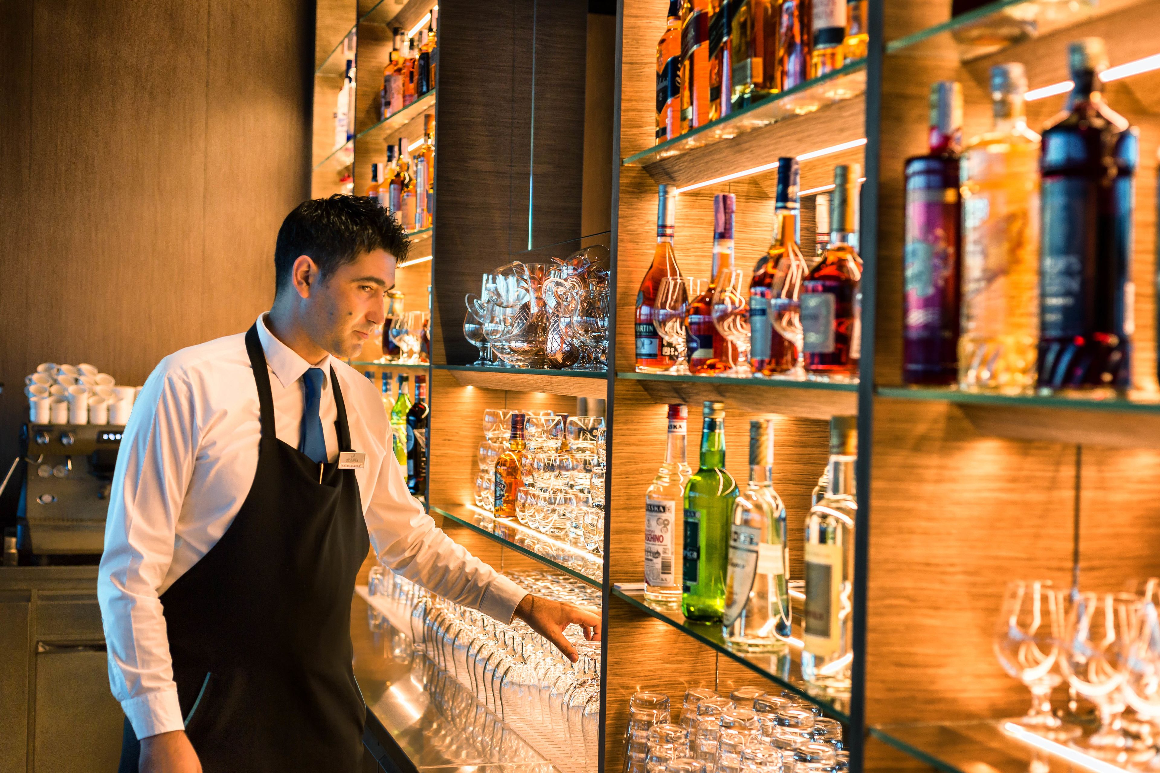 A bar area with shelves stocked with various liquor bottles and glasses.