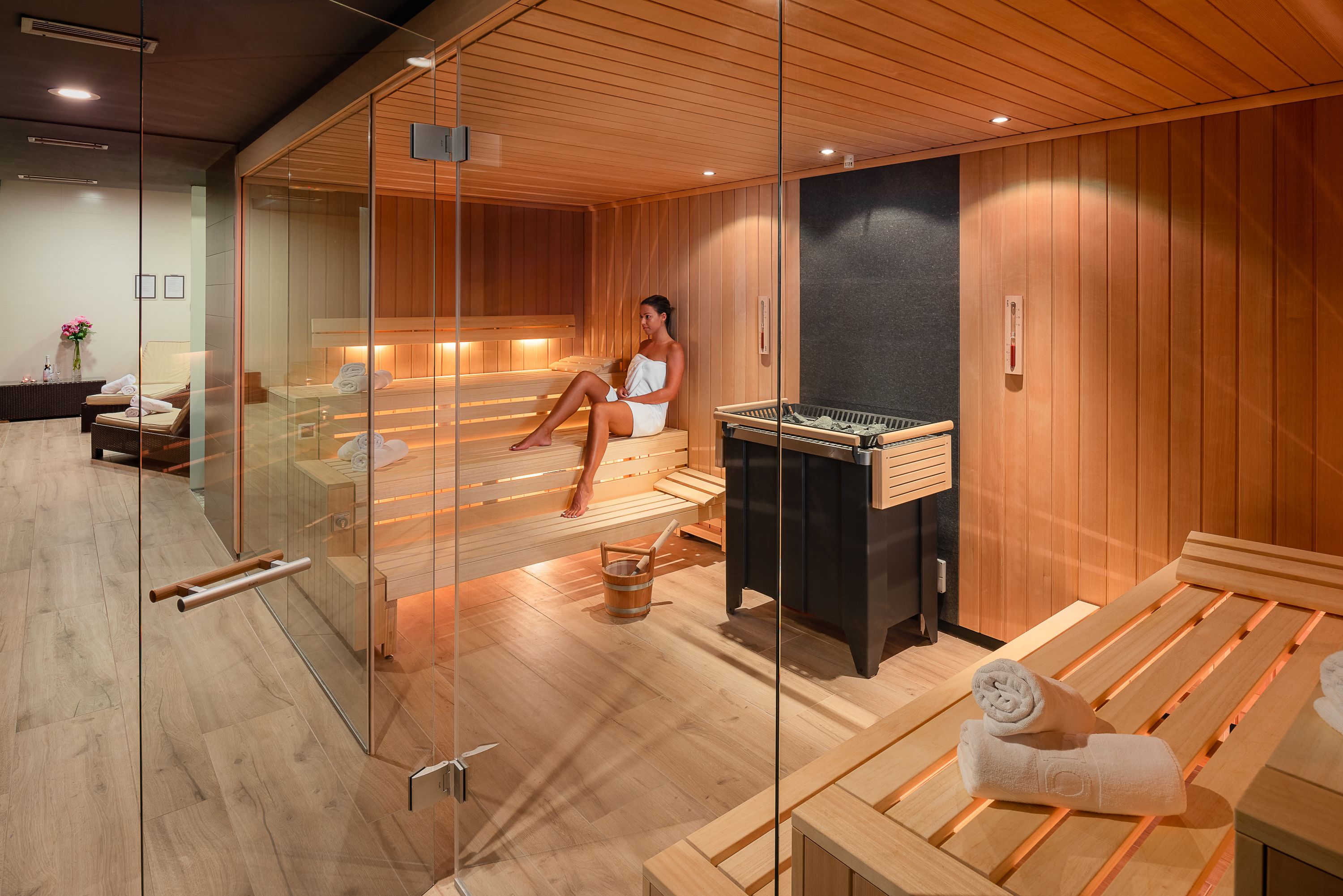 Una sauna moderna con bancos de madera y un panel de vidrio.