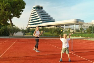Una cancha de tenis con un edificio moderno al fondo.