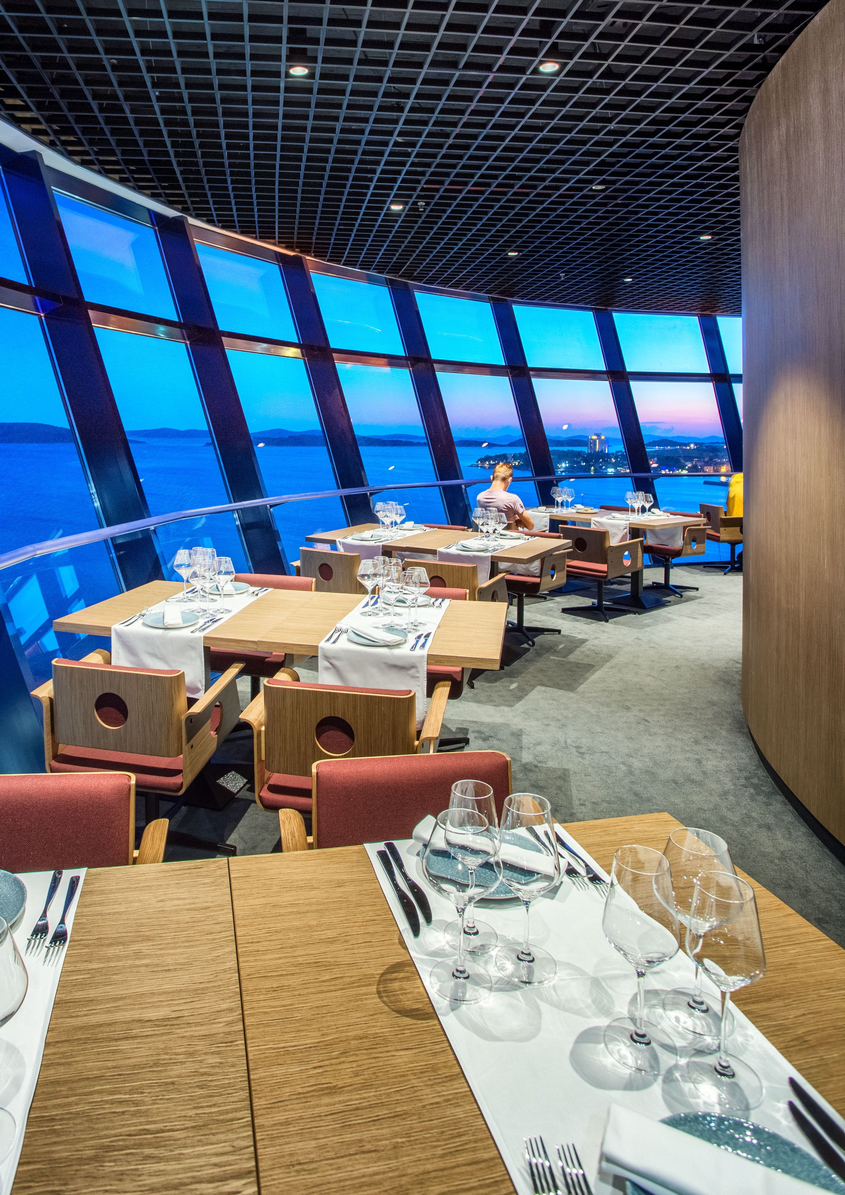 Un restaurante con mesas dispuestas para comer, que ofrece vistas amplias a través de grandes ventanales.