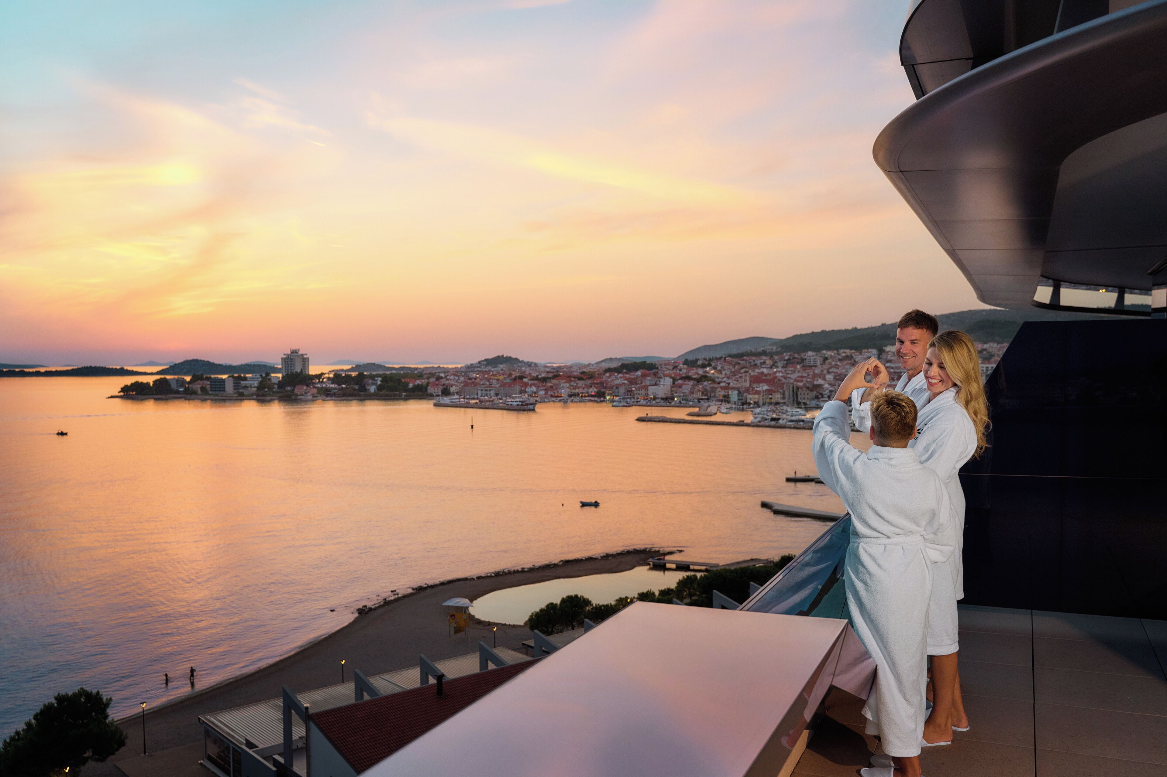 A couple taking a selfie with a cityscape and water in the background.