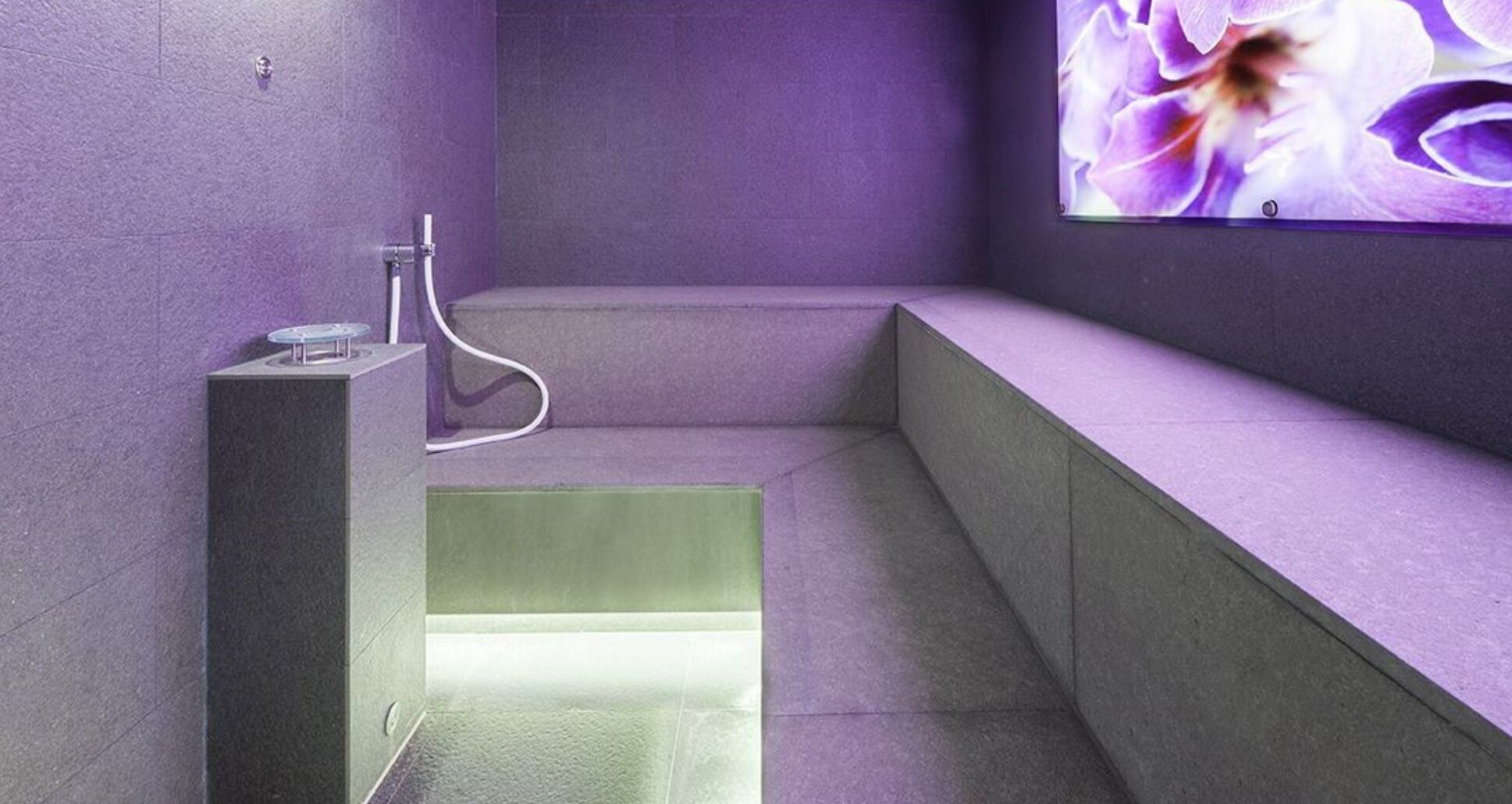 A modern bathroom with a built-in shower, a bench, and a wall-mounted mirror.