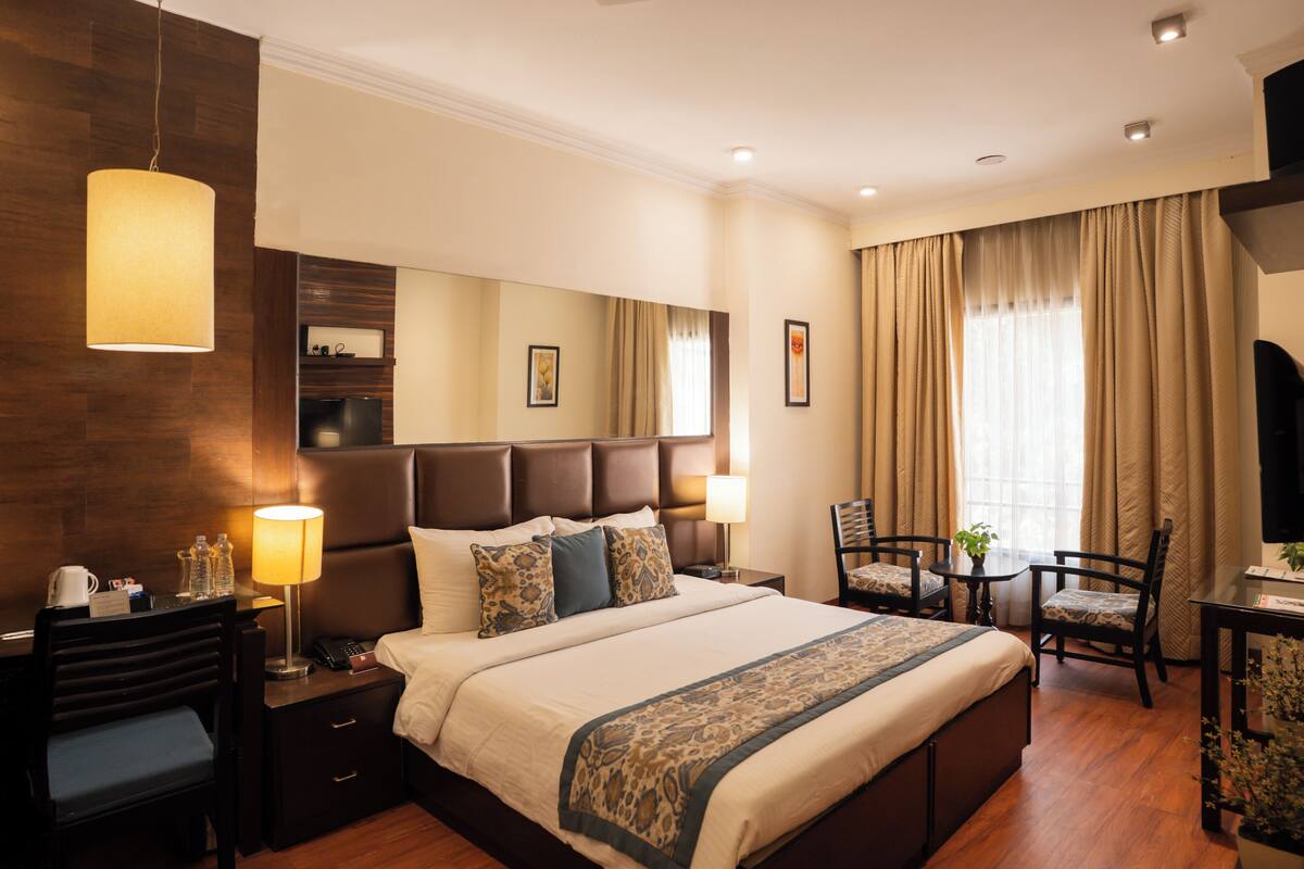 Habitación de hotel con una cama grande, mesitas de noche, un escritorio y una silla.