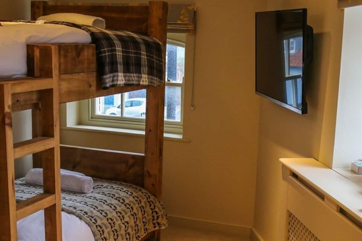A bunk bed room with a television and a window.