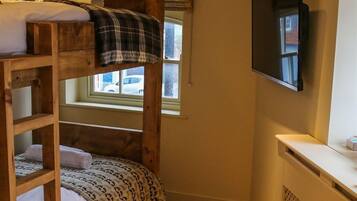 A bunk bed room with a television and a window.
