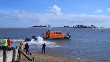 A boat on a calm body of water with people on the shore.