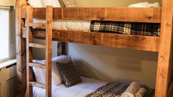A bunk bed with a ladder, white bedding, and a plaid blanket.