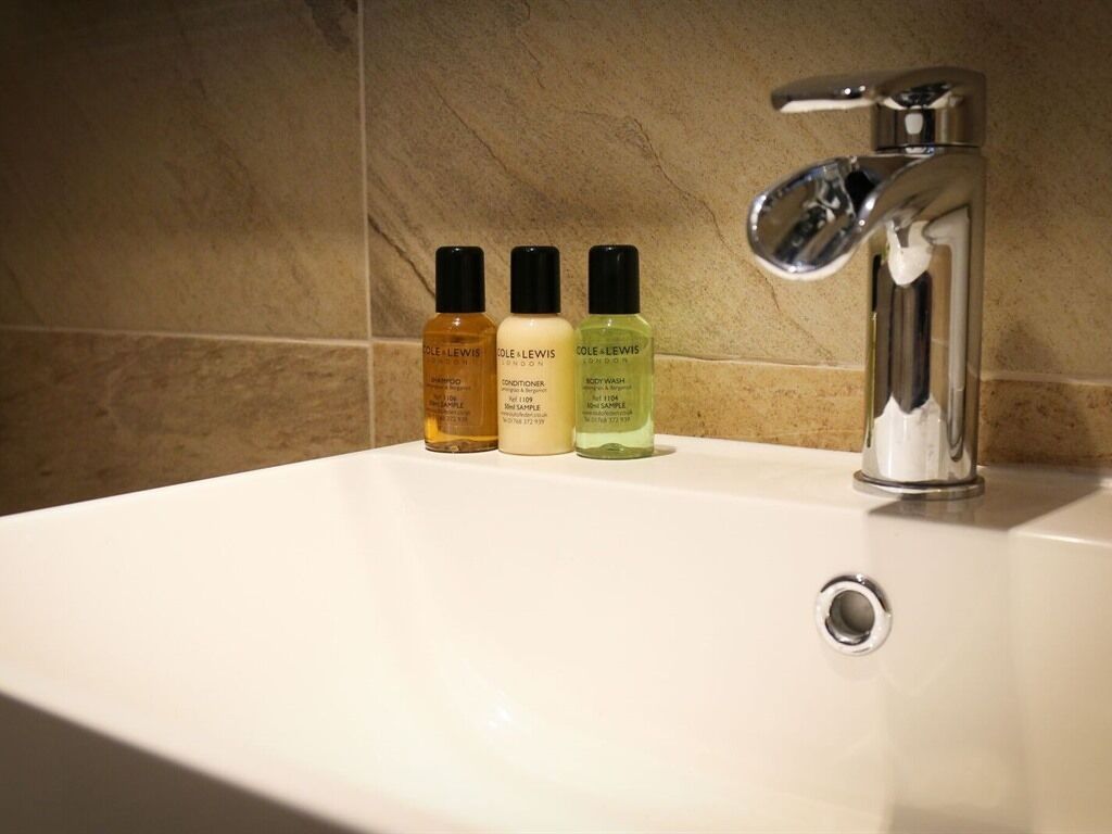 A bathroom sink with three bottles of body wash.