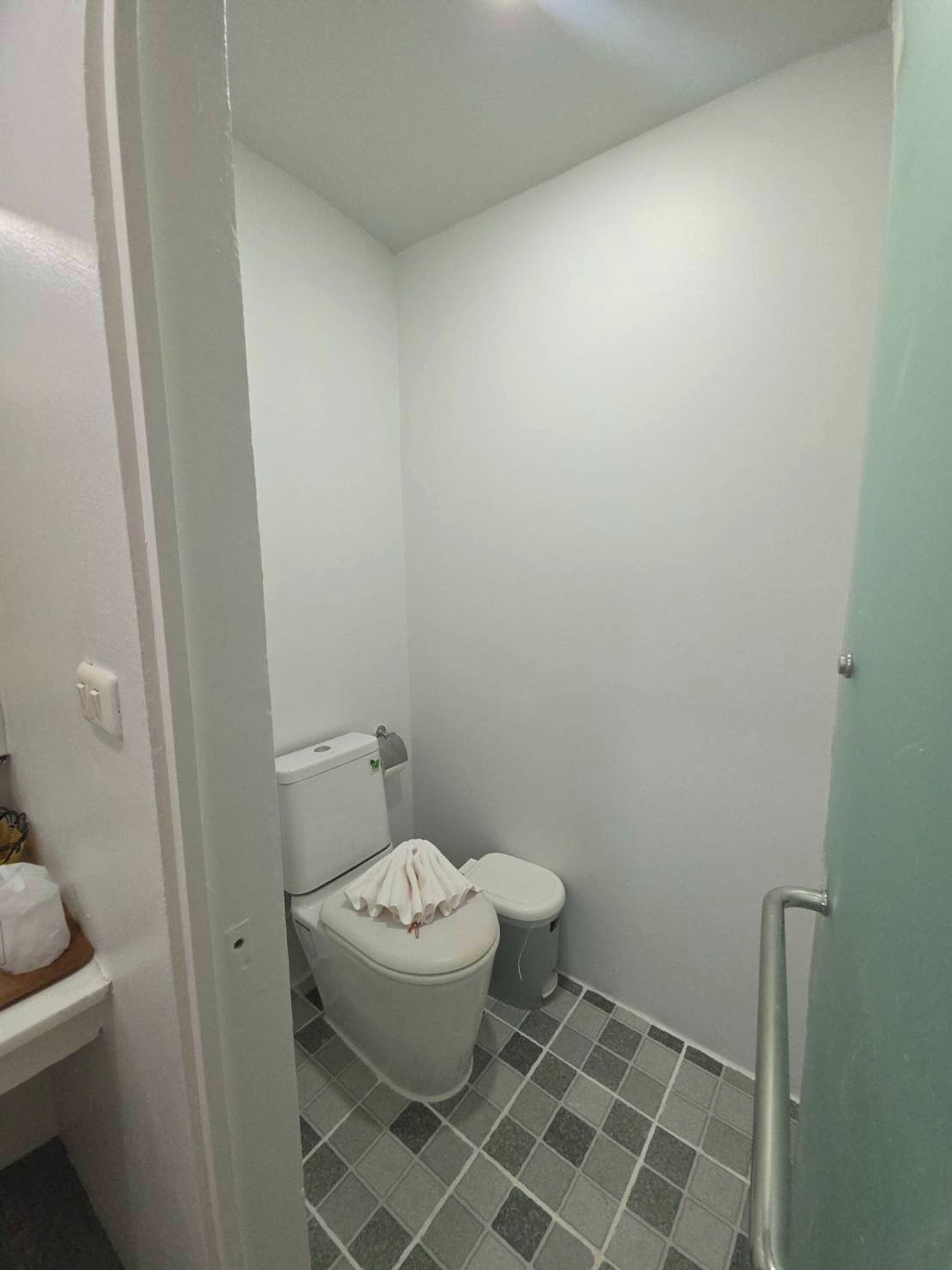 A small, clean bathroom with a toilet, a trash bin, and a tiled floor.