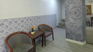 Una habitación con una mesa de comedor y dos sillas, un papel tapiz decorado y una columna de mármol.