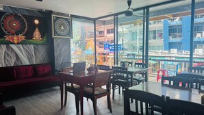 Un restaurante con una decoración moderna, un comedor con mesas y sillas, y un amplio ventanal con vistas a la ciudad.