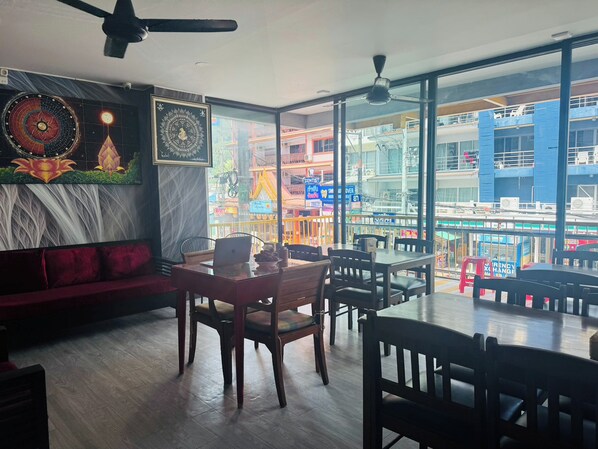 A restaurant with a modern interior, a dining area with tables and chairs, and a large window offering a view of the city.