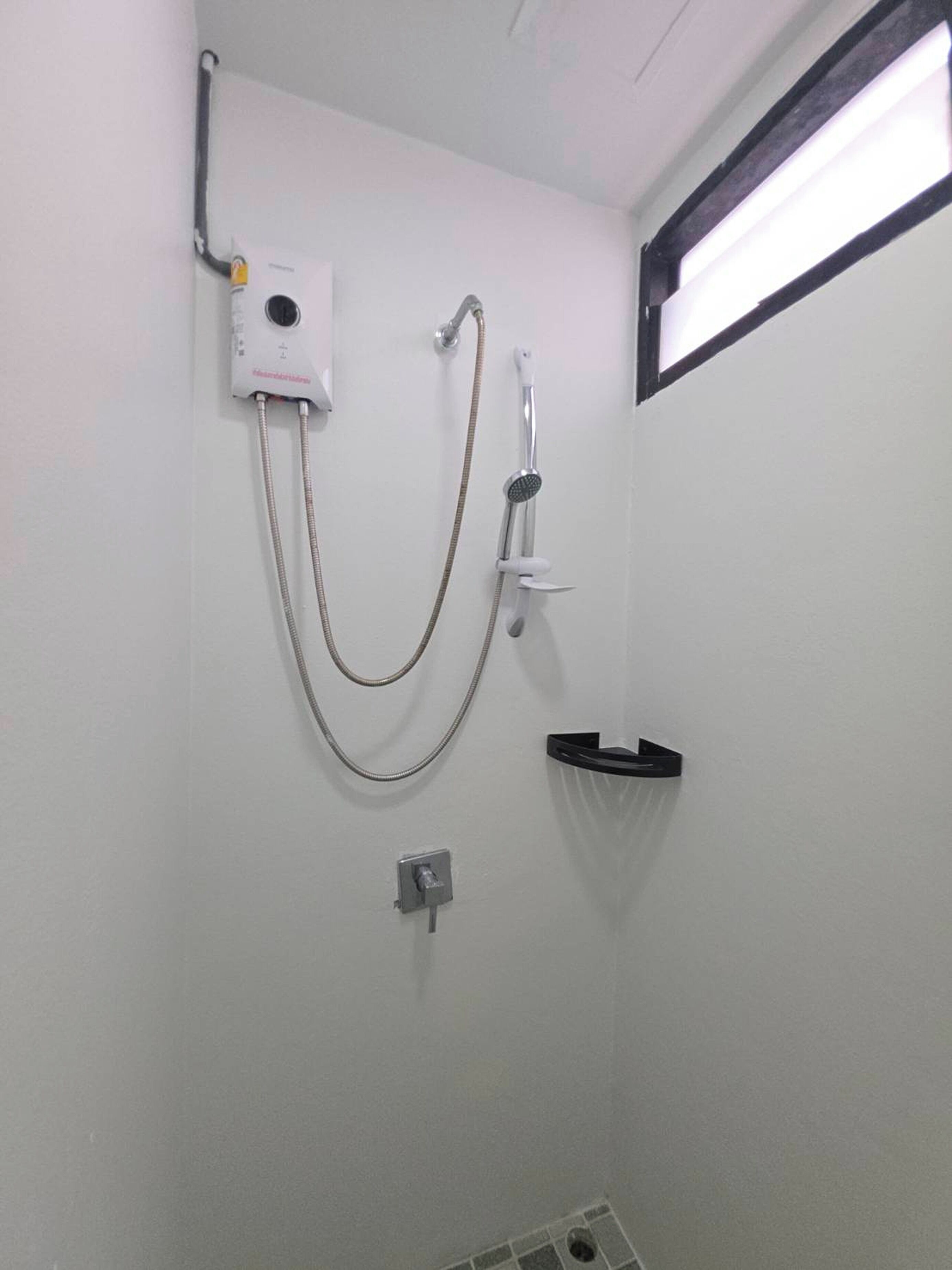A shower with a handheld showerhead and a wall-mounted control panel.