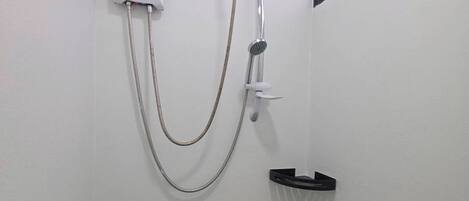 A shower with a handheld showerhead and a wall-mounted control panel.