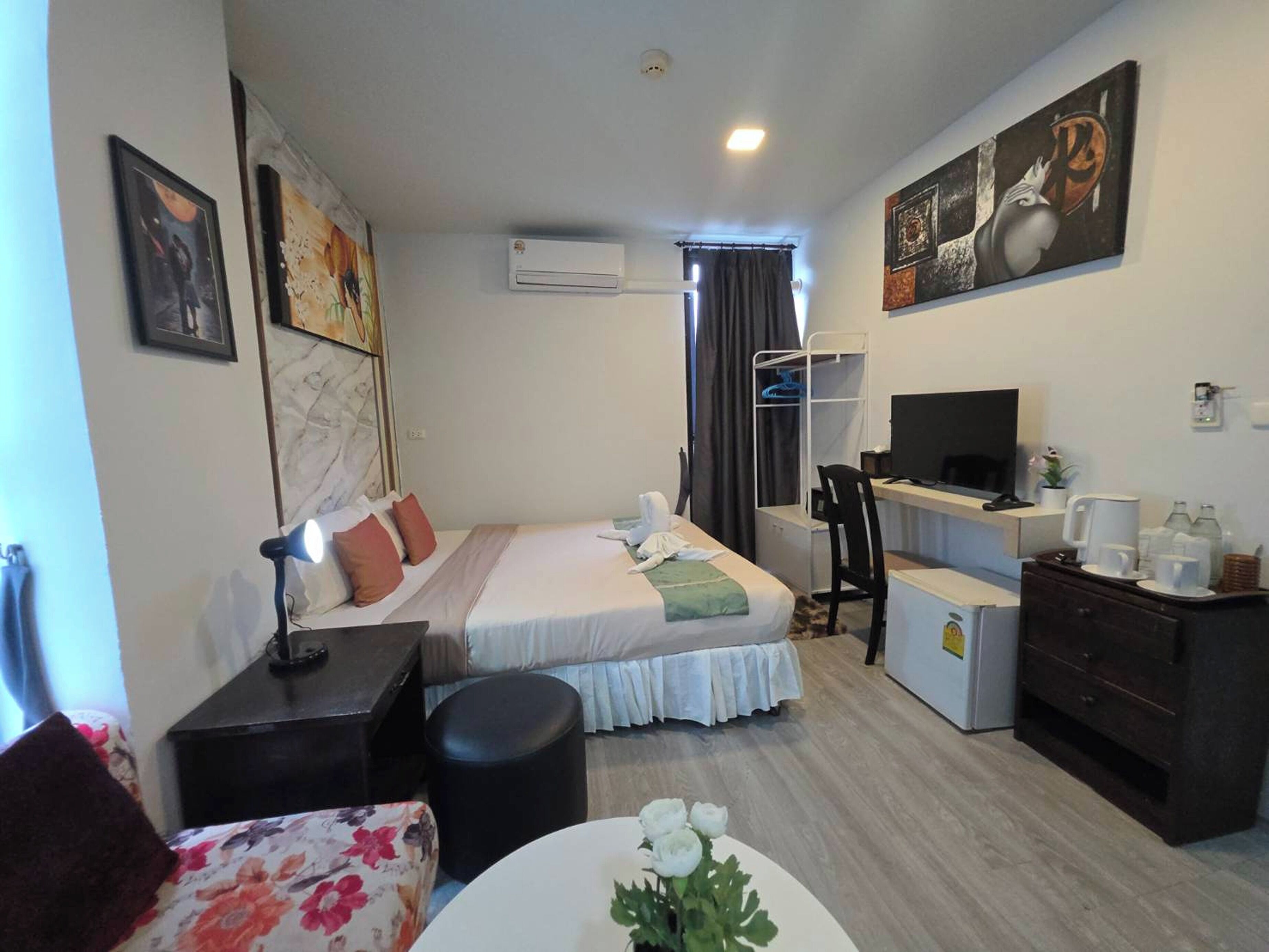 A hotel room with a bed, desk, chair, and a small refrigerator.