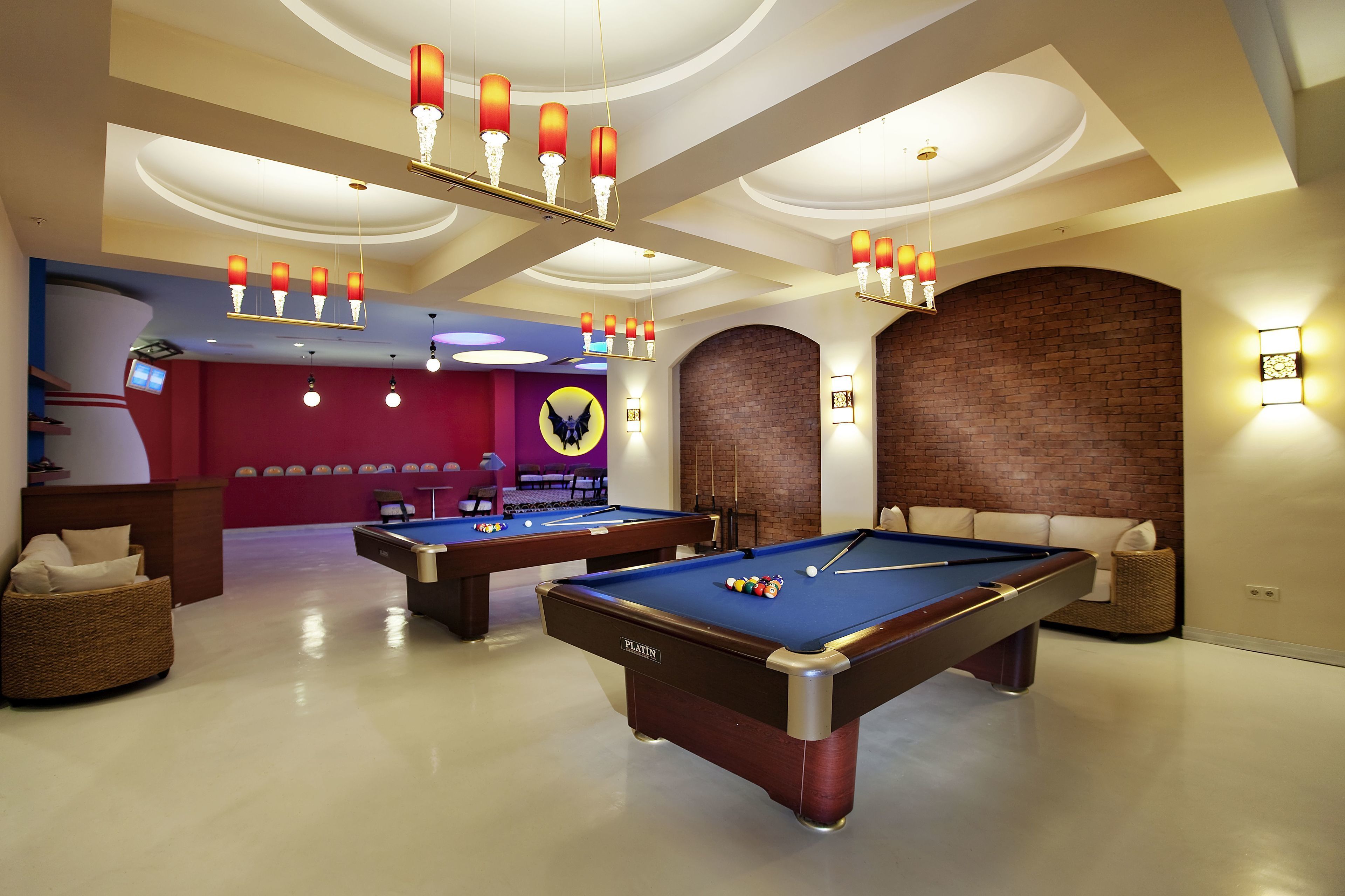 A pool table with a billiard cue, a lounge area with a sofa, and a brick wall.
