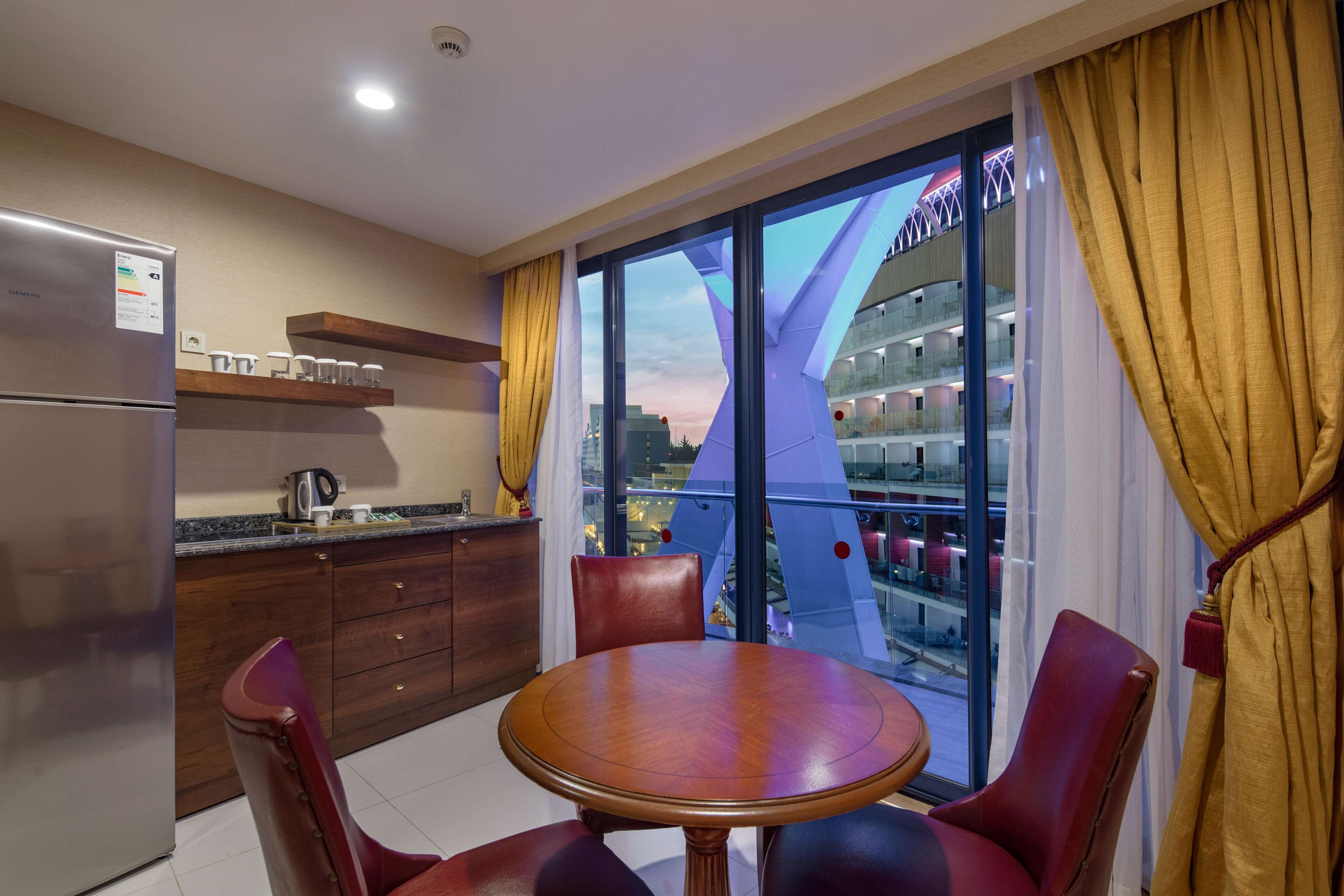 A modern kitchen with a built-in refrigerator, wooden cabinets, and a dining area with a round table and chairs.