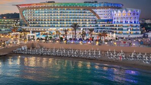 A large hotel with multiple floors, outdoor seating areas, and a waterfront view. - Granada Luxury Resort Okurcalar - All Inclusive (Alanya)