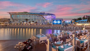 Ein Hotel am Wasser mit mehreren Restaurants, einer großen beleuchteten Signage und Blick auf das Meer.