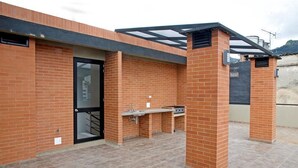An outdoor patio with a brick wall, a glass door, and a grill area. - Las Palmas Apartment 306 (Bogotá)