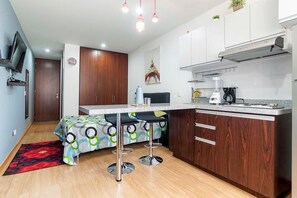 A compact kitchen with a dining area, wooden cabinets, a built-in stove, and a small bar stool set.