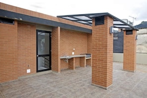 Eine Terrasse im Freien mit Backsteinmauer, Glastür und Grill.