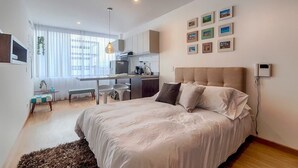 Une chambre moderne avec un grand lit, un bureau et un coin cuisine.
