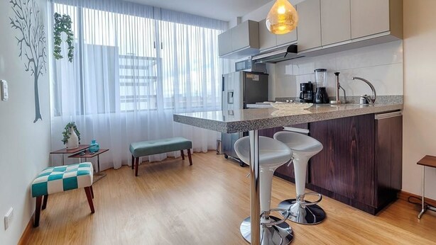 Une cuisine moderne dotée d’un îlot central, de tabourets de bar et d’un coin repas avec une banquette.