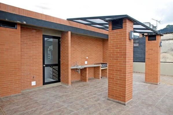 An outdoor patio with a brick wall, a glass door, and a grill area.