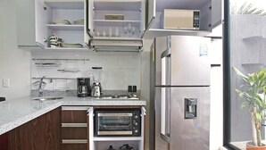 Une cuisine compacte équipée d’un four encastré, d’une machine à café et d’un four à micro-ondes posé sur le plan de travail.