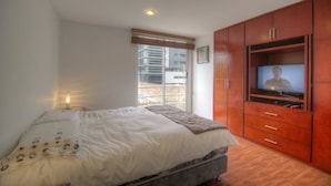 Un dormitorio con cama, televisión y ventana.