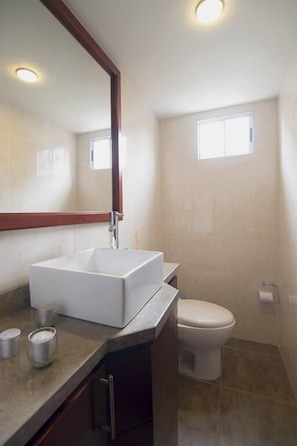 A bathroom with a rectangular sink, a toilet, and a window.
