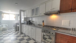 Una cocina con armarios blancos, estufa a gas, microondas y un lavamanos.