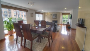 Un salón espacioso con comedor, ventanas amplias y vista a un edificio.