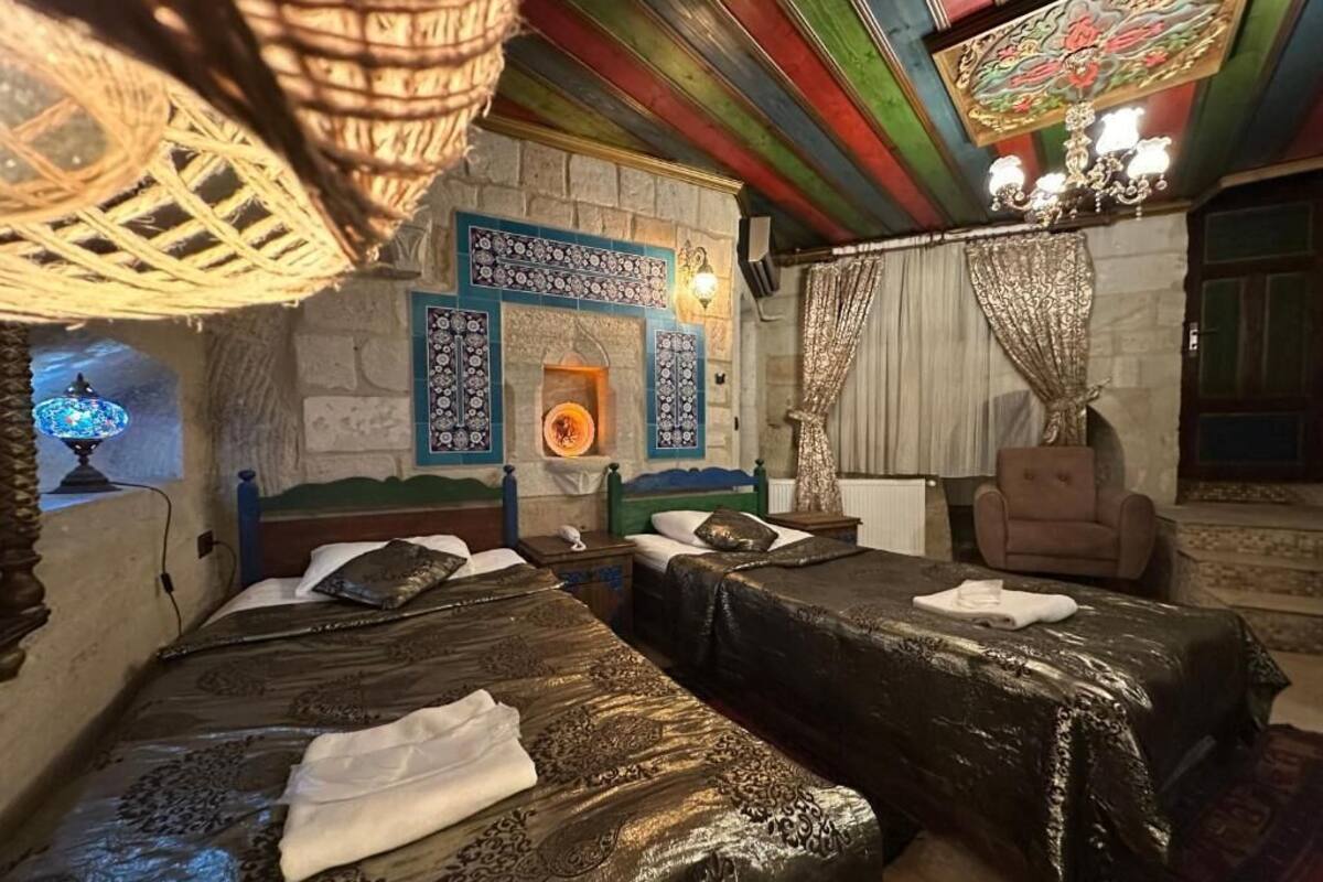 Quarto com duas camas, um candelabro, parede estampada e uma cadeira tradicional.