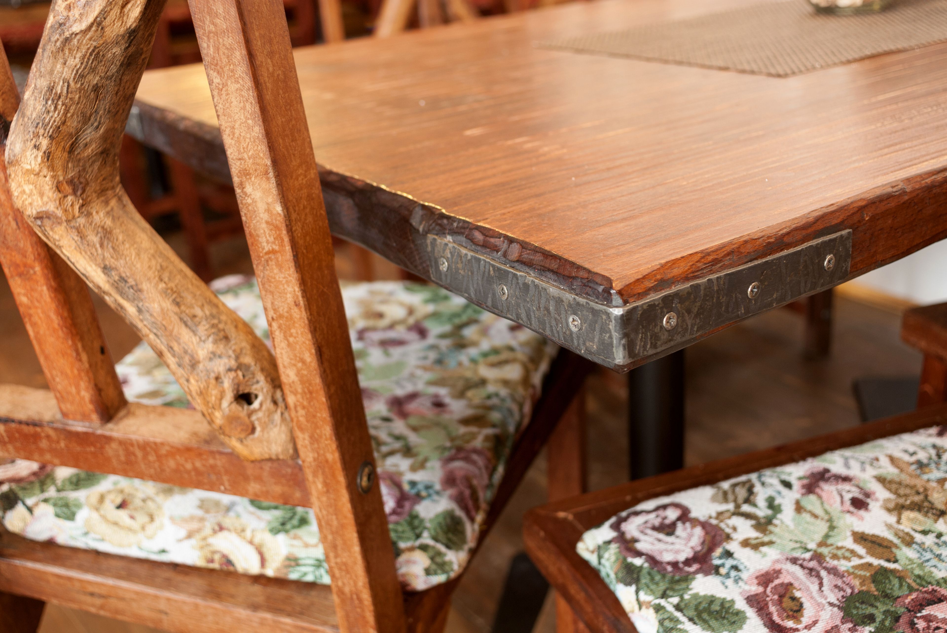 A wooden table with metal brackets and floral-patterned chairs.
