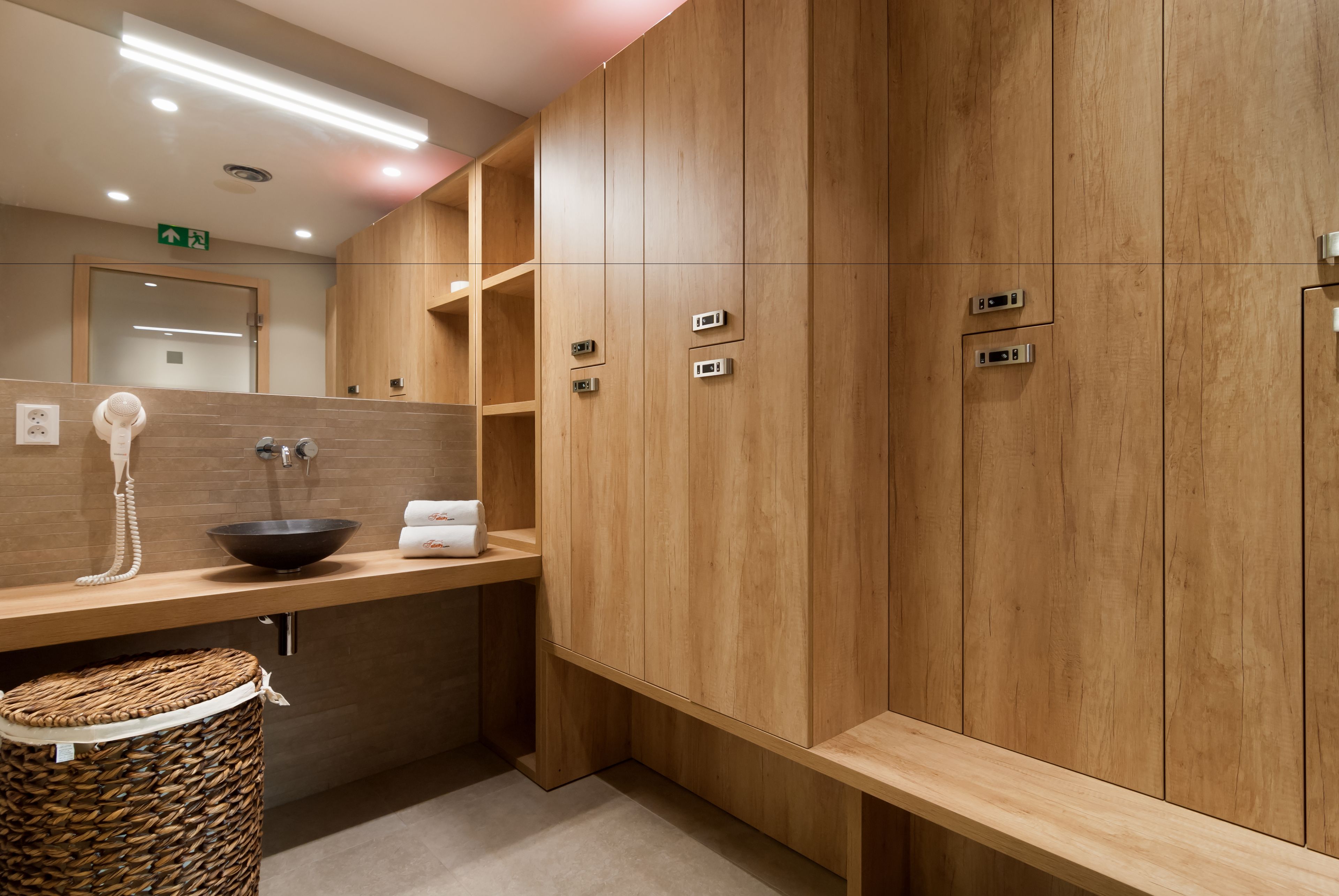 Un baño moderno con armarios de madera, un lavabo, un perchero para toallas y un cesto de basura.